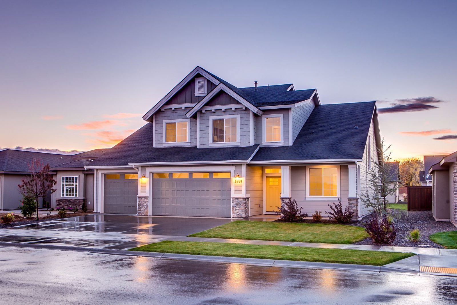 A suburban house at dusk with the lights on
