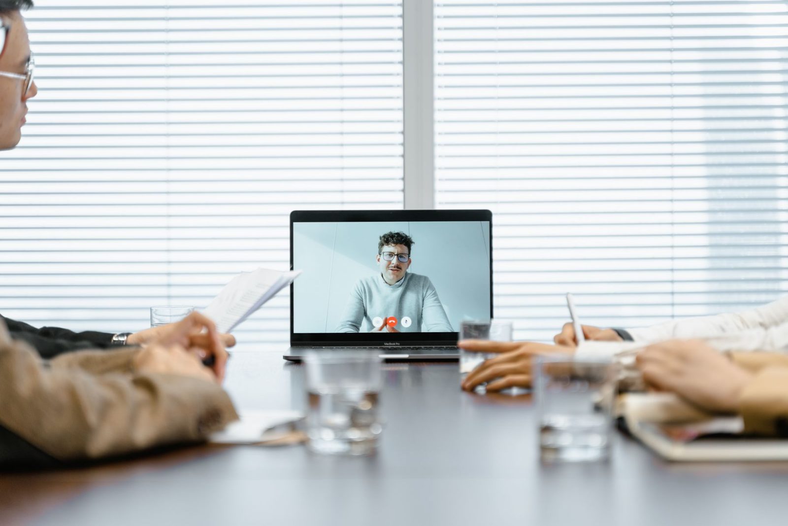 A laptop on a meeting table showing a video call